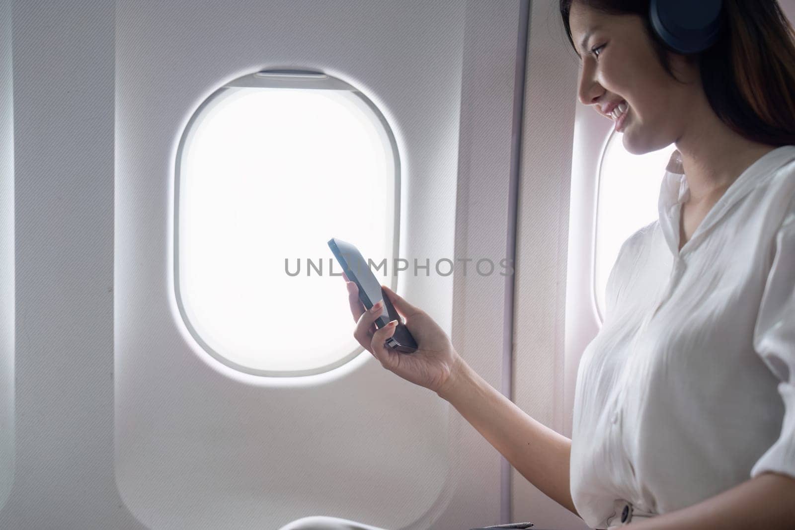 Modern Technology in Flight Travel, Passenger Using Smartphone on Airplane by nateemee