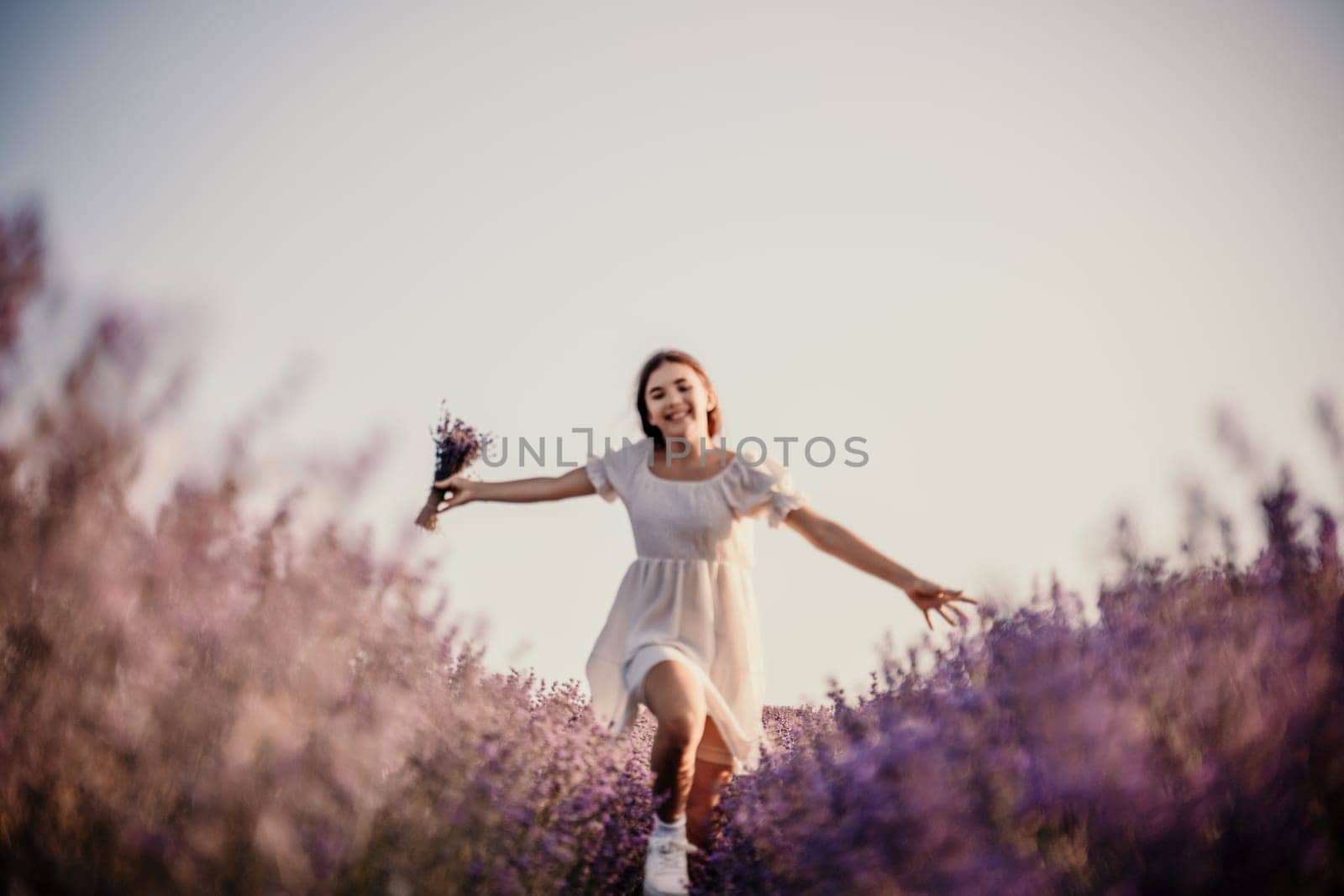 Lavender field happy girl in white dress with a scythe runs through a lilac field of lavender. Aromatherapy travel by Matiunina
