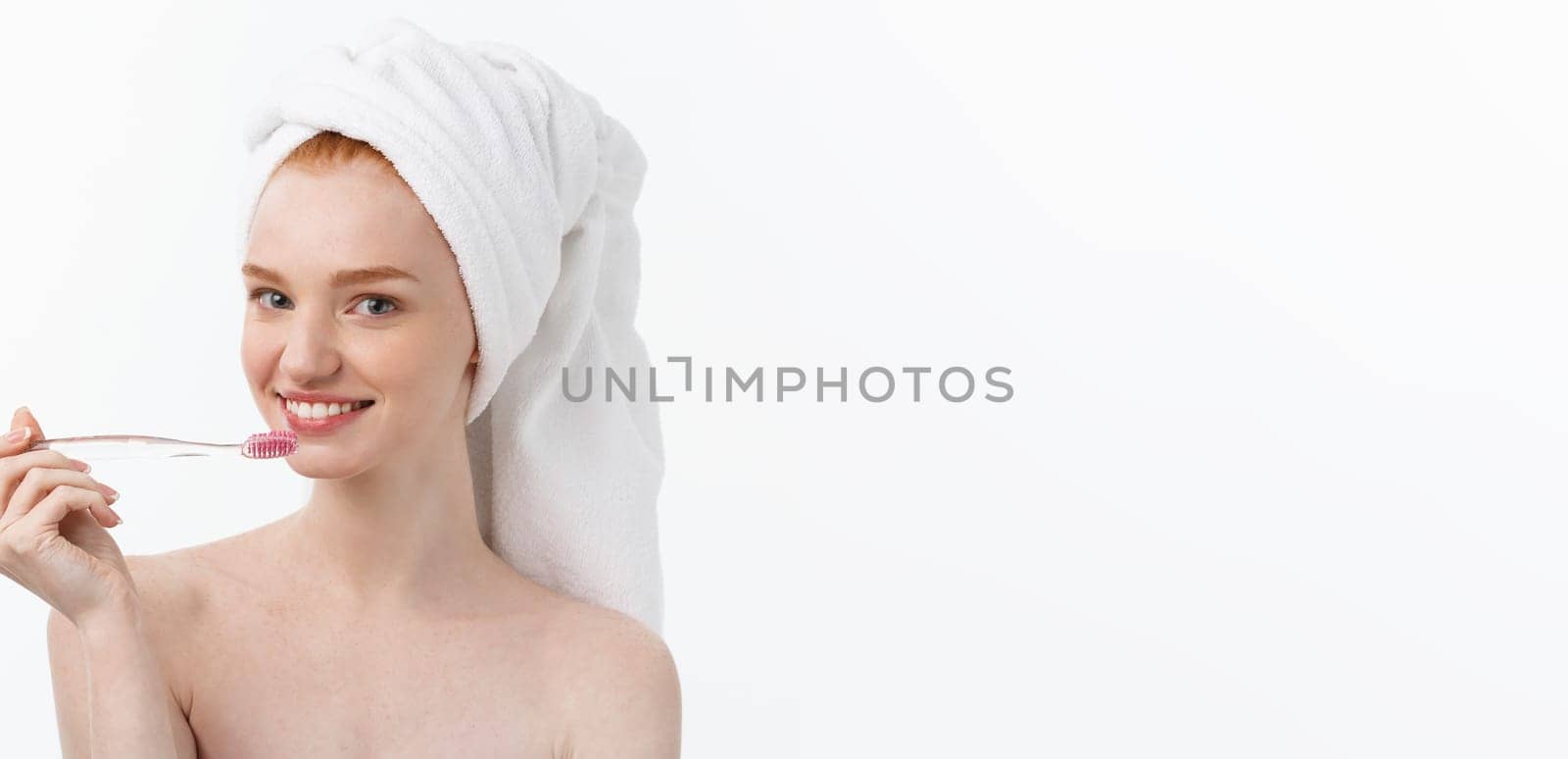 Portrait of young woman with toothbrush on grey background