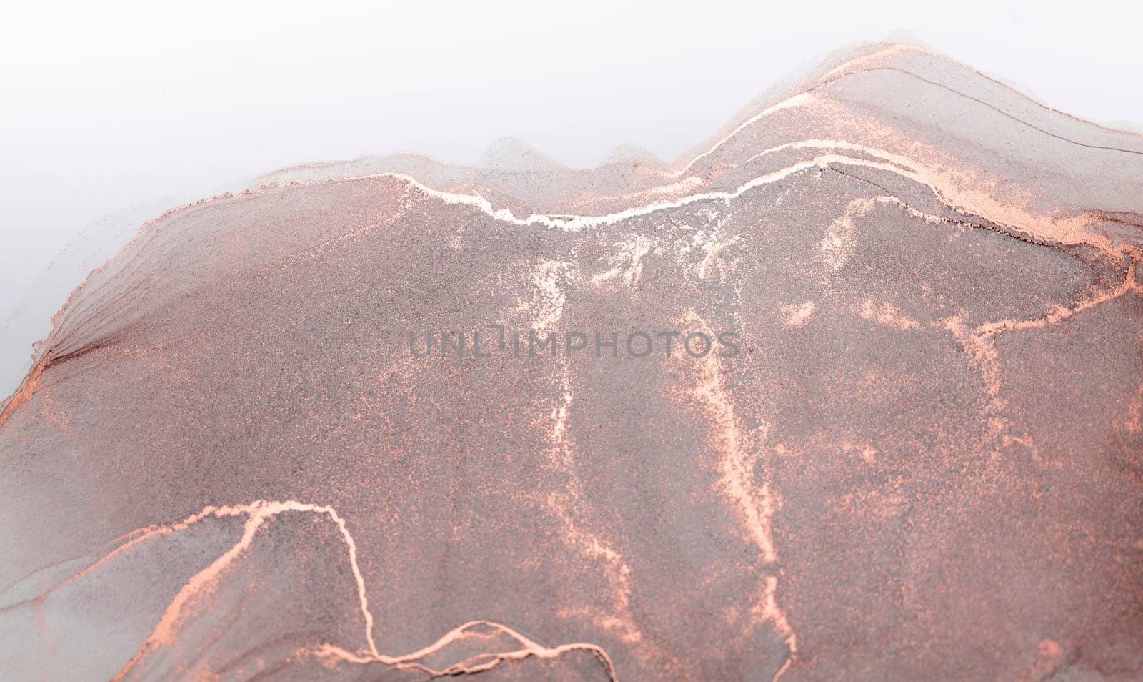 A close-up abstract image of a rose-gold mountain range emerging from the mist, with delicate veins of white running through it.