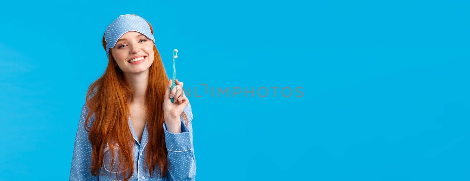 Health, lifestyle and beauty concept. Cheerful cute glamour redhead woman in nightwear and sleep mask, smiling happily, start morning brushing teeth and taking care personal hygiene.