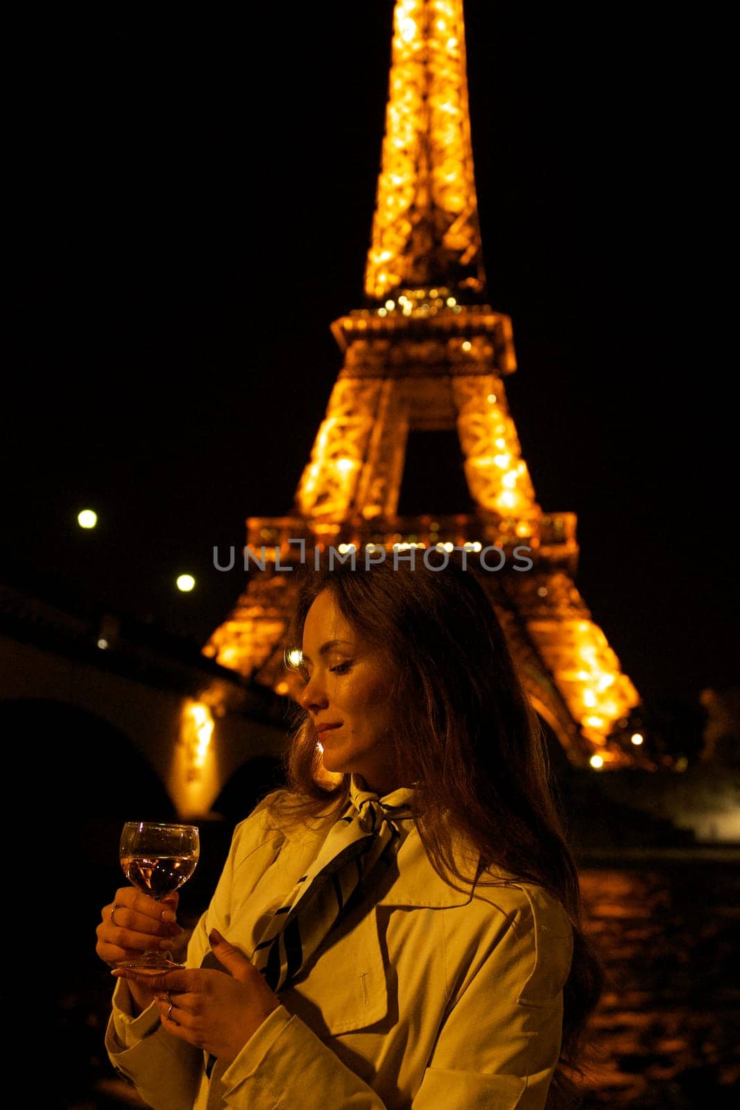 Girl with a glass against the backdrop of the glowing Eiffel Tower in. High quality photo