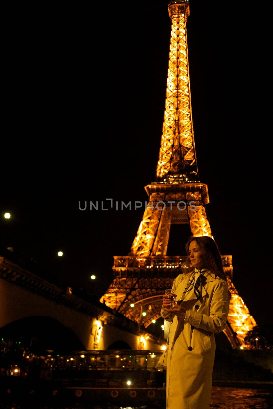 Girl with a glass against the backdrop of the glowing Eiffel Tower in. High quality photo