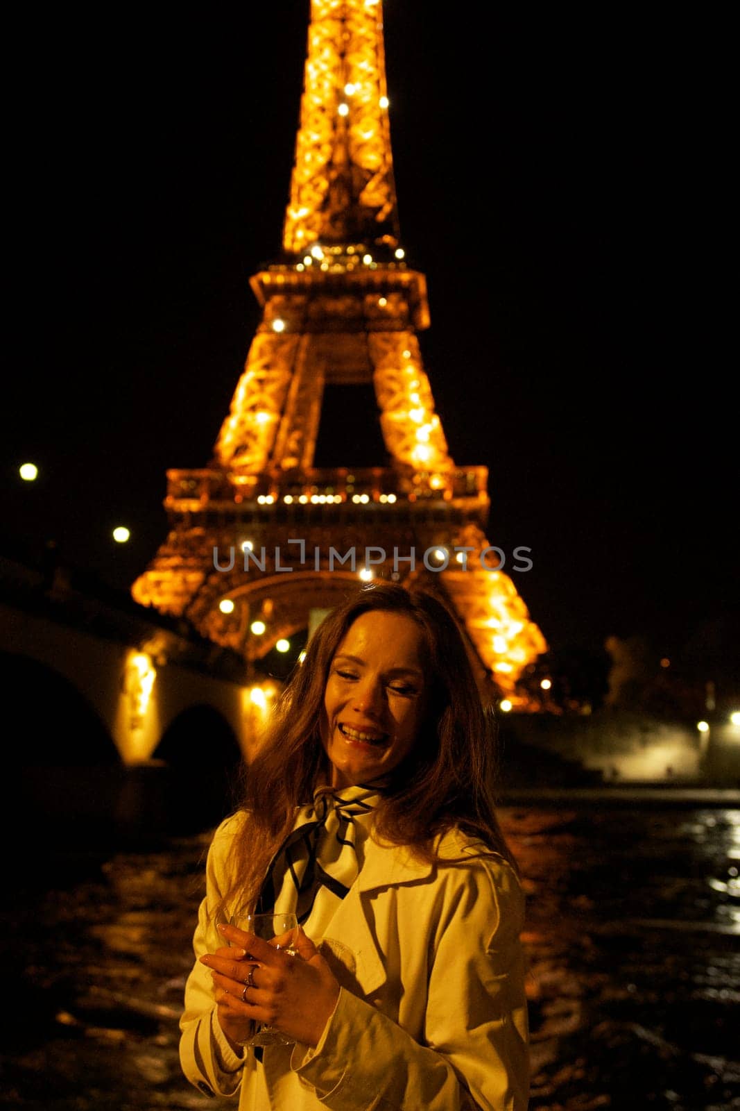 Girl with a glass against the backdrop of the glowing Eiffel Tower in. High quality photo