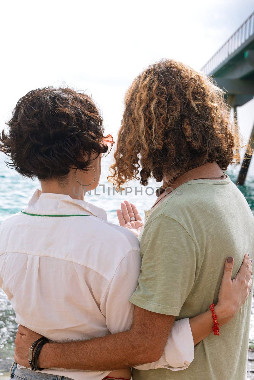 Rear view two happy friends on the beach on vacation,looking at the sea. by mariaphoto3