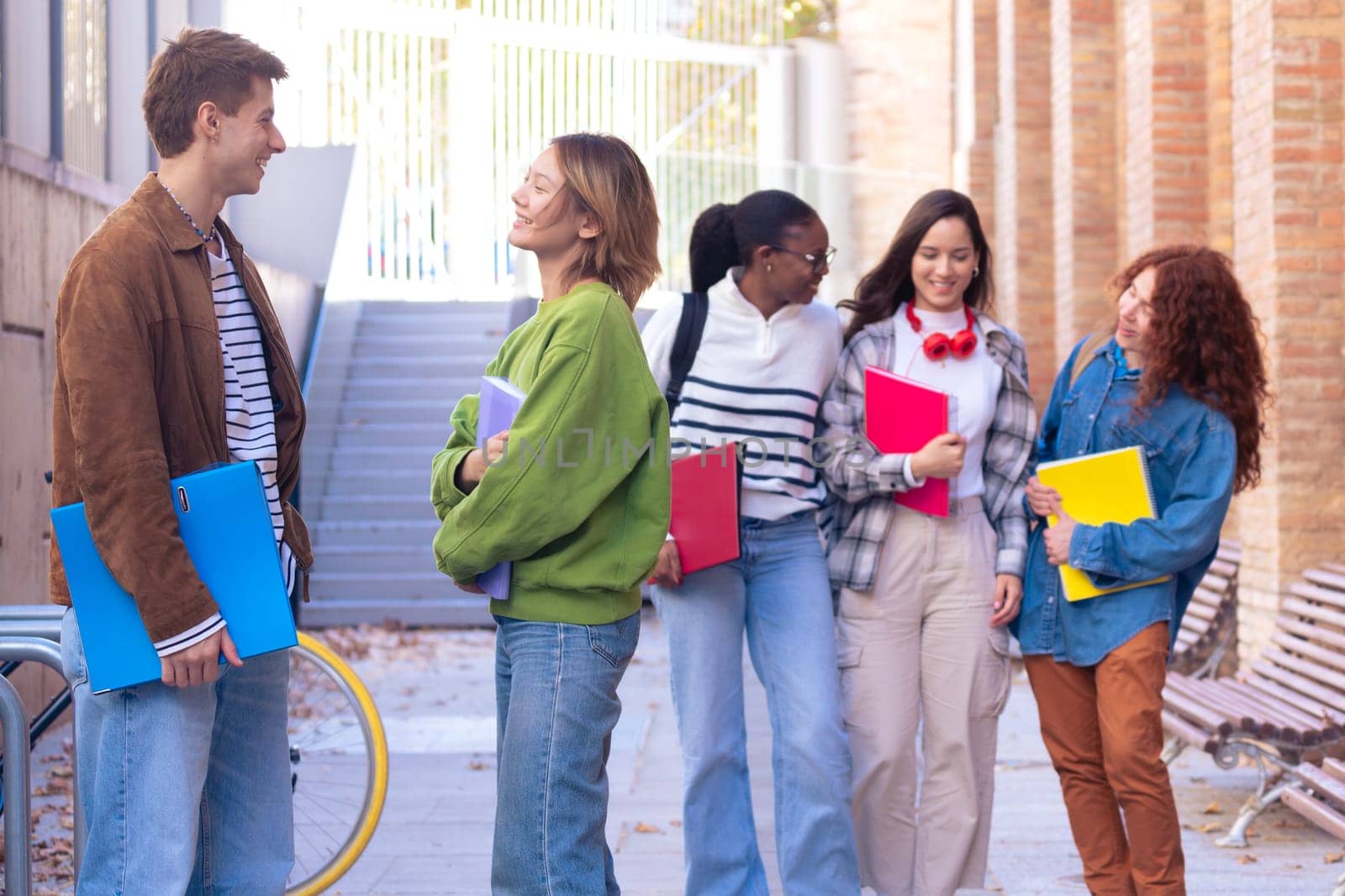 Multiracial group of students walking around college campus laughing outdoors Young community of people having fun together.