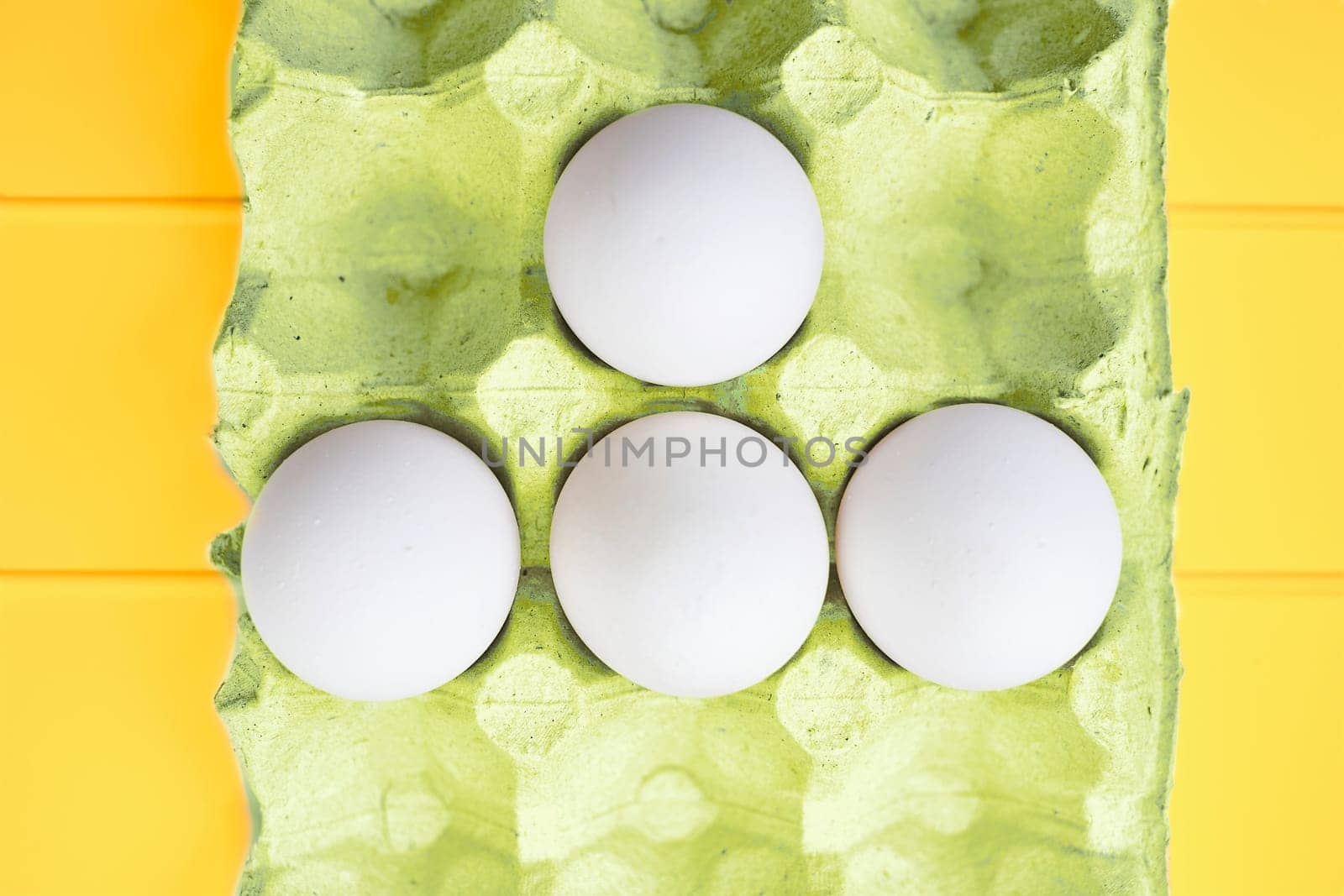 Abstract four white eggs in a packing carton on a plastic surface by jovani68