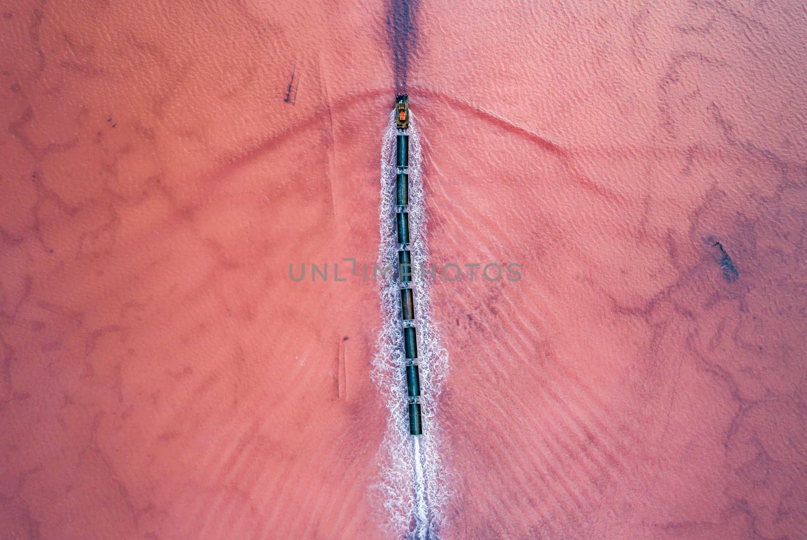 Aerial top down view of an old train rides on the railway laid in the water through the salt lake. Salt mining in Lake Burlin. Altai. Bursol.