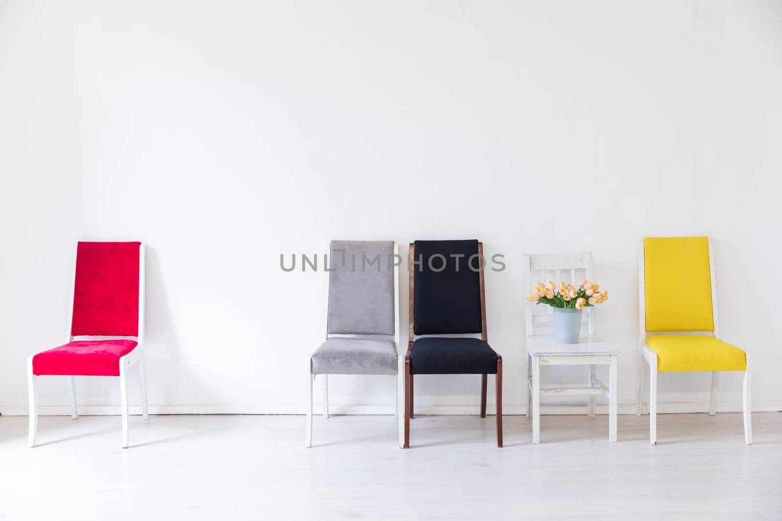 a grey red yellow black chairs with flowers in the interior of the white room