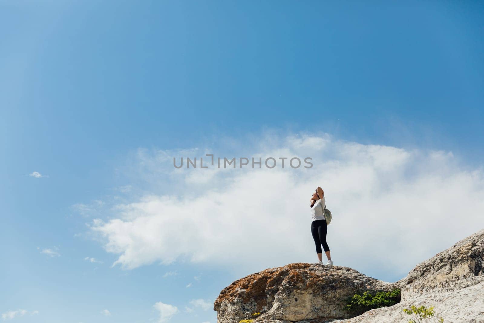 woman standing on a mountain under a blue sky hiking journey on foot