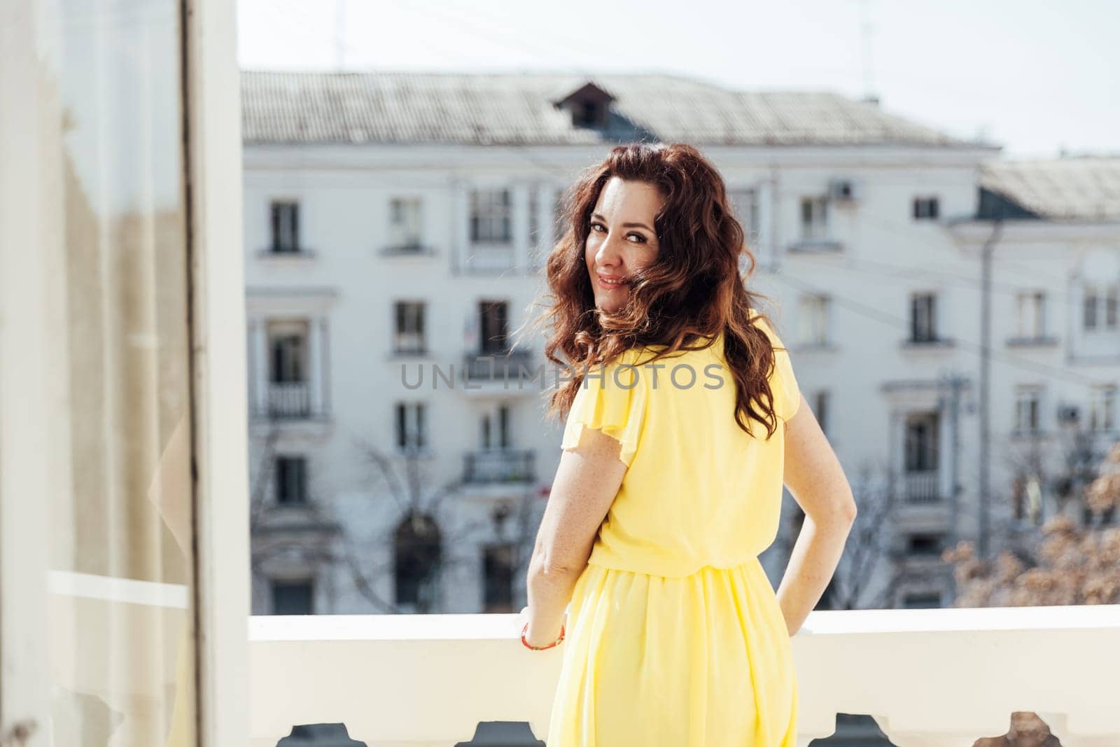 a beautiful brunette woman standing on the balcony in the apartment fresh air