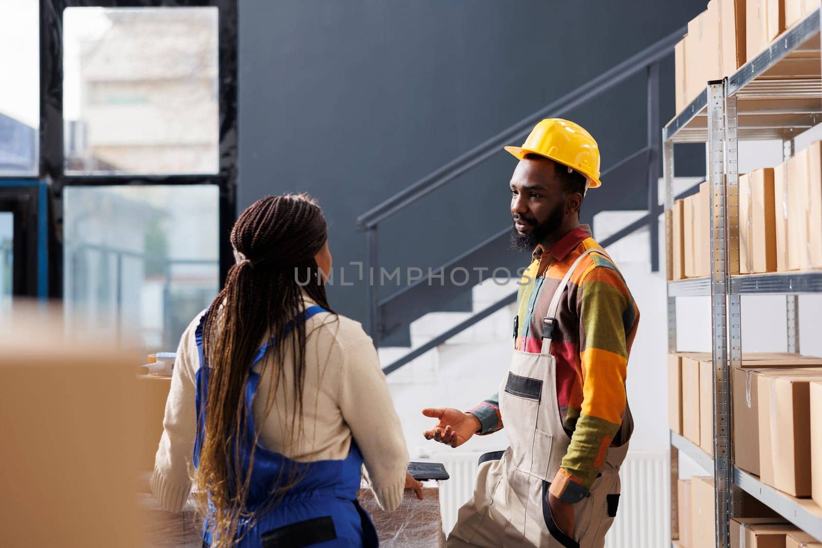 African american warehouse worker explaining colleague parcel packing instruction by DCStudio