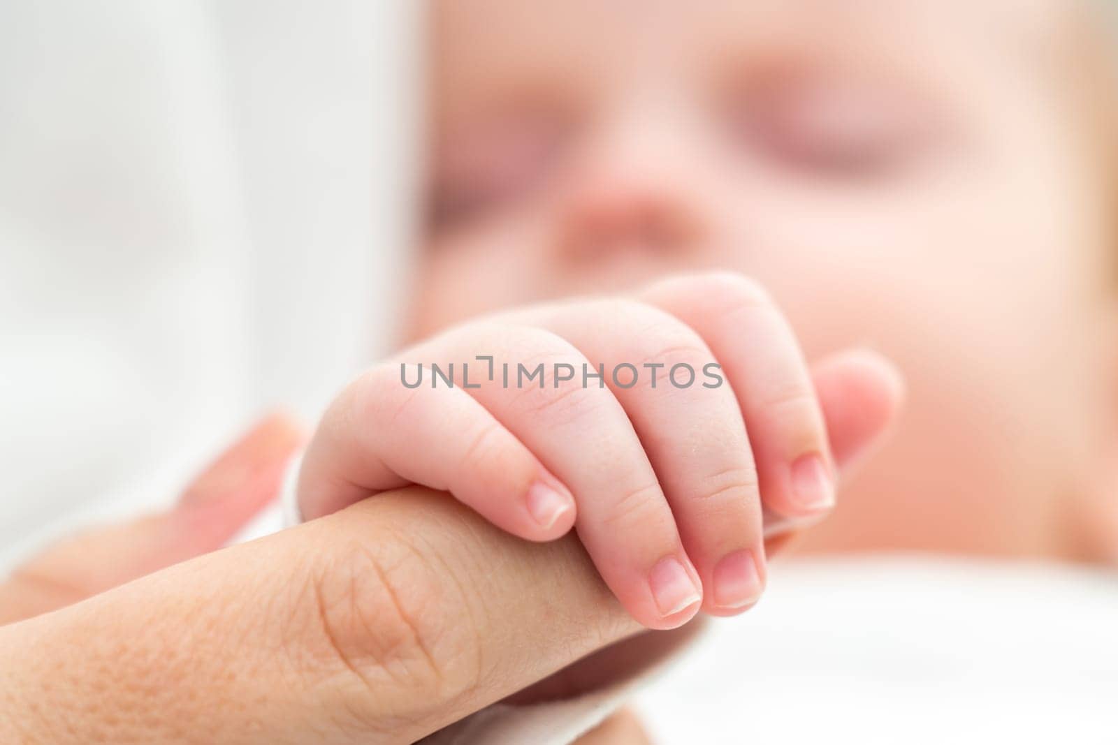 The tender touch of a sleeping newborn, tightly holding the mother's finger, embodies love and assurance