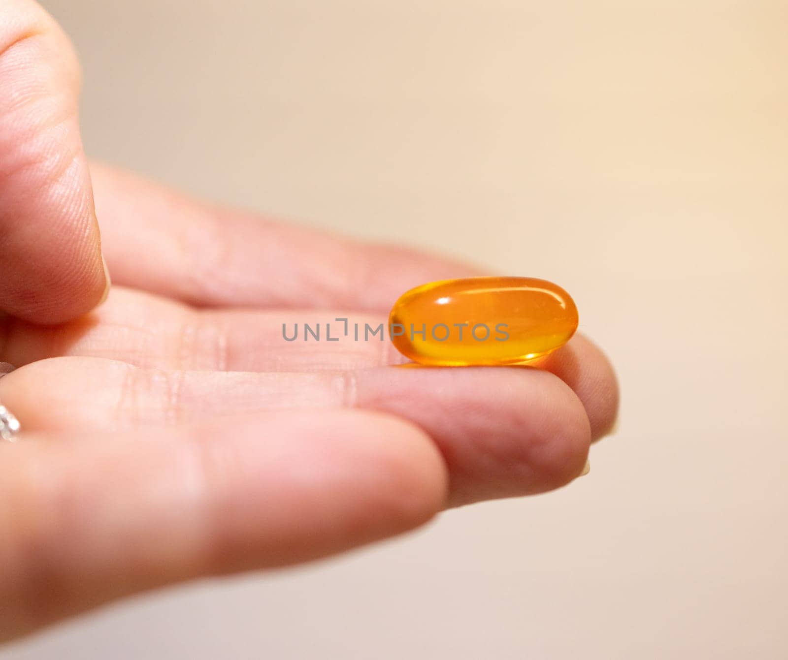 Close-up photo of hand holding a transparent soft capsule. by VeroDibe