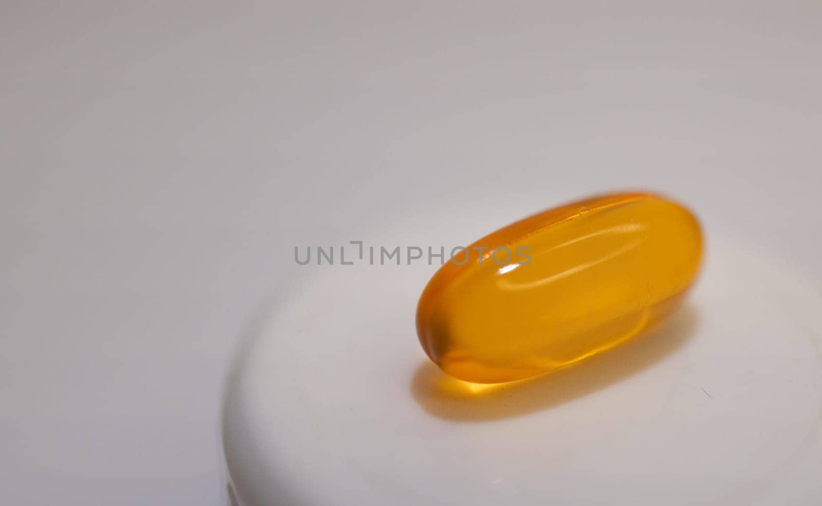 Close-up of soft capsule of vitamins on light background. by VeroDibe