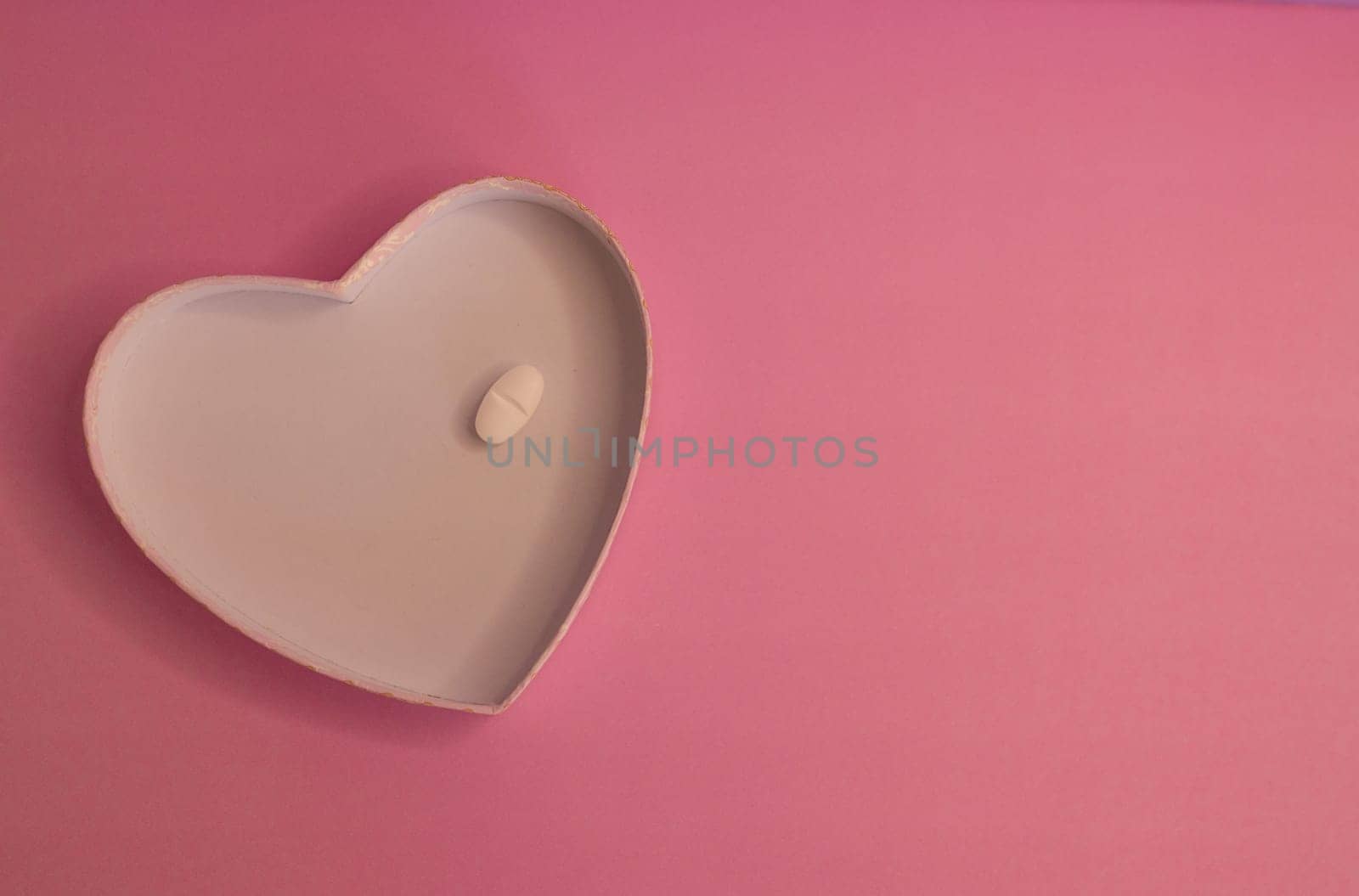 Heart-shape plate with white capsule on pink background by VeroDibe