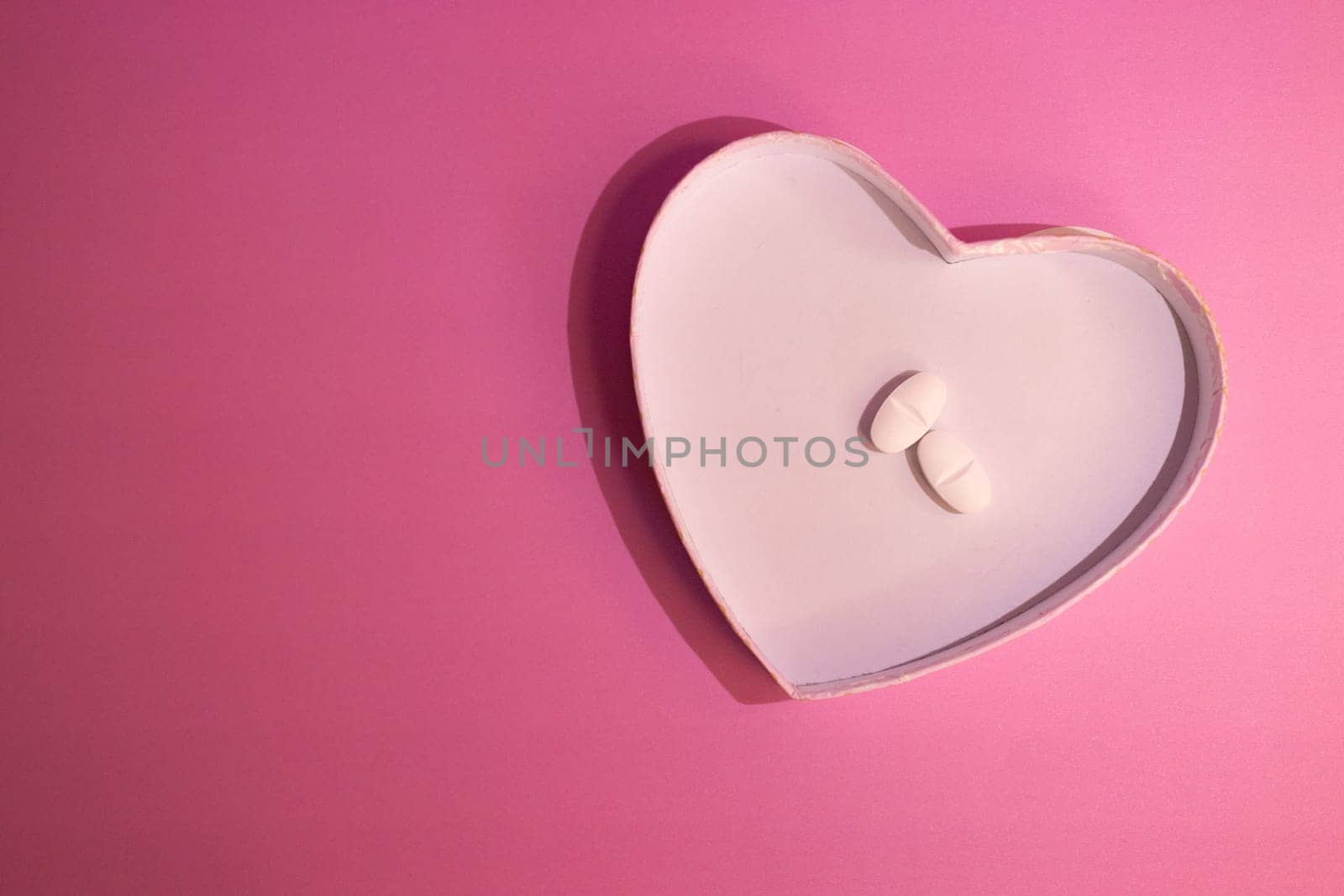 Concept of heart care. Graphic resource to promote body care and health.Horizontal top view photo with space for copy on pastel pink background.