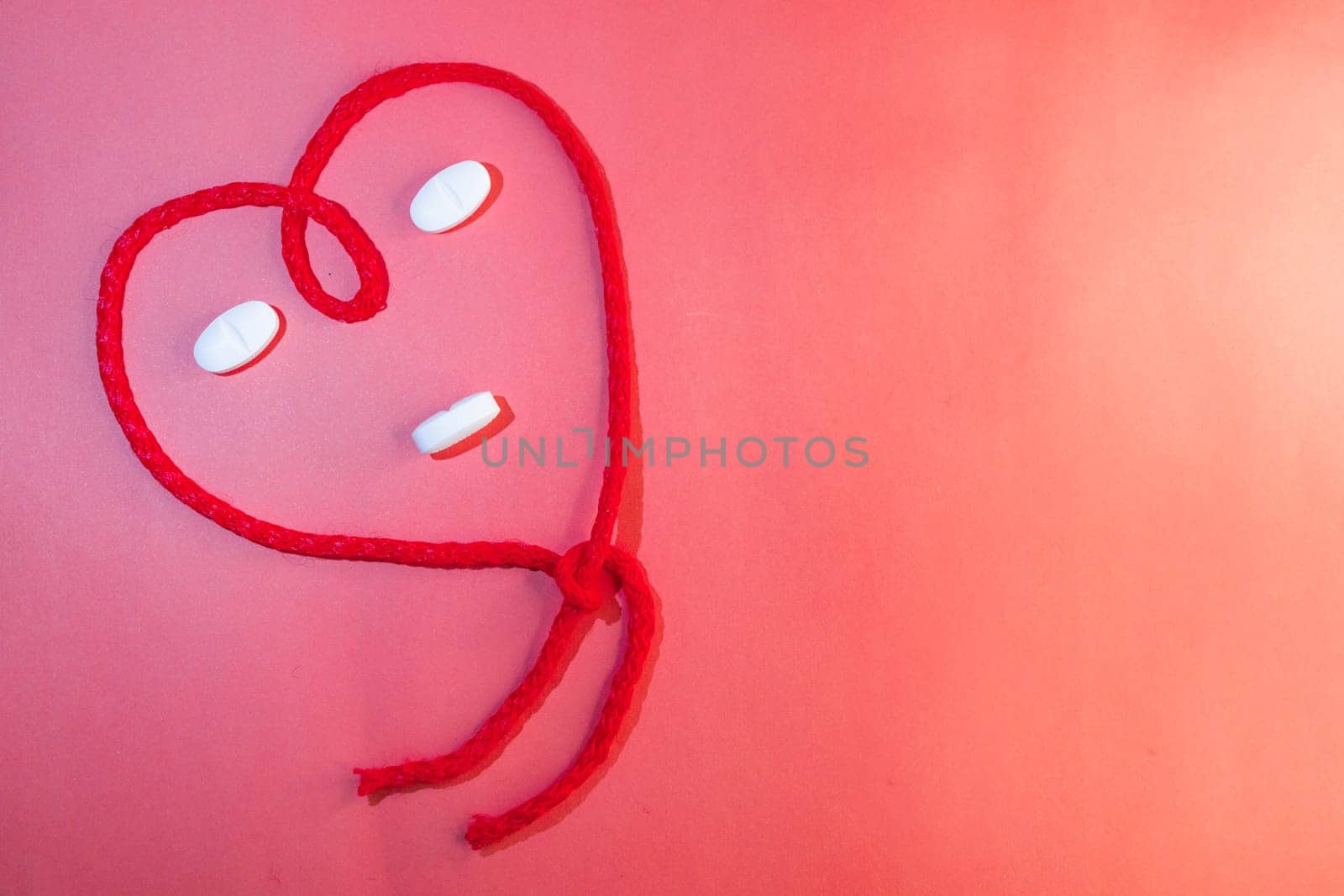 Top view of red string in the shape of a heart simulating a face. Copy space by VeroDibe