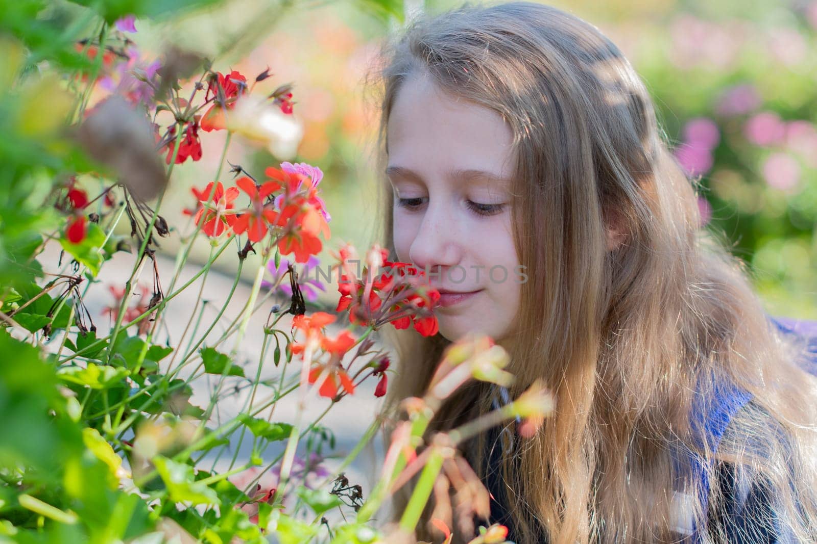 Back to school, portrait of little blonde elementary school girl outdoors enjoying flowers with smile, student dressed in dark blue uniform
