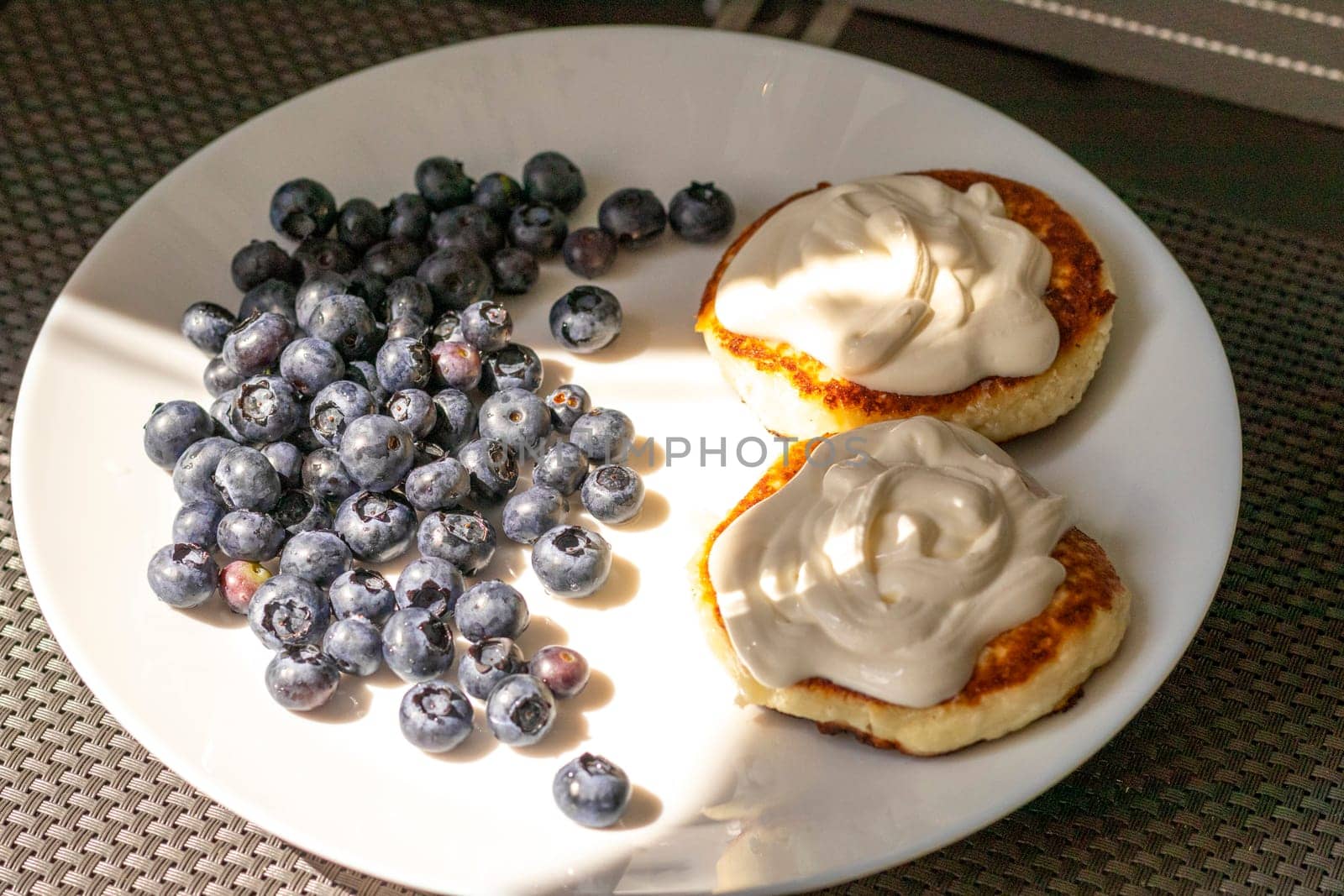 Shot of the breakfast plate with home made cheesecakes with sour cream and blueberries