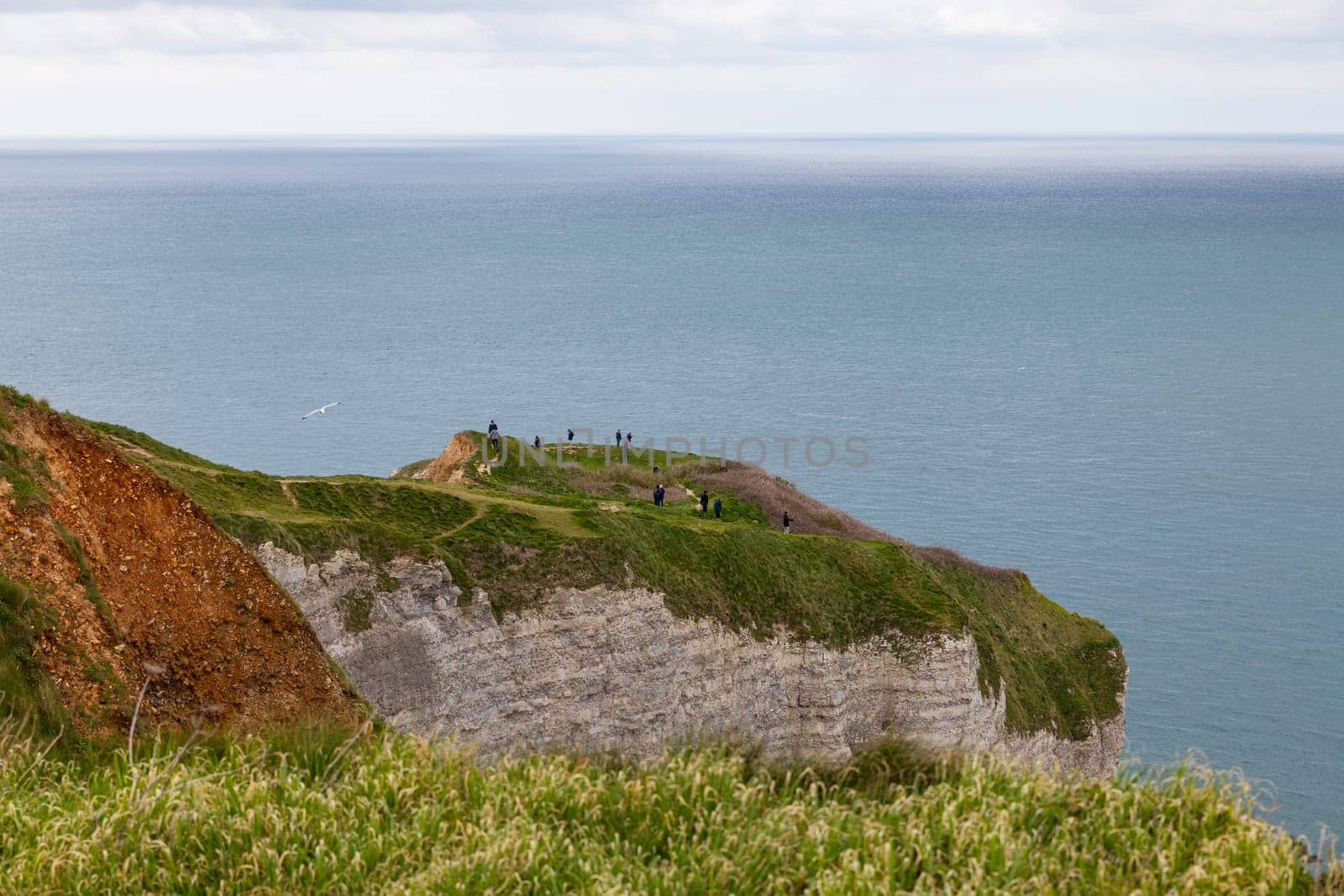 etretat,france,23-04-2024:people walking on the rocks and cliffs of etretat in france looking at the ocean