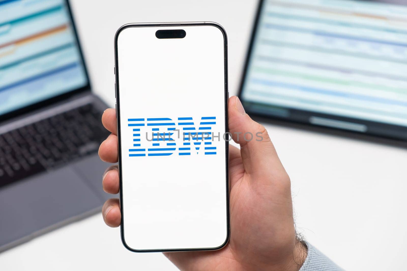 PRAGUE, CZECH REPUBLIC - JANUARY 21 2024: IBM logo on the screen of smartphone in mans hand on the workplace background.