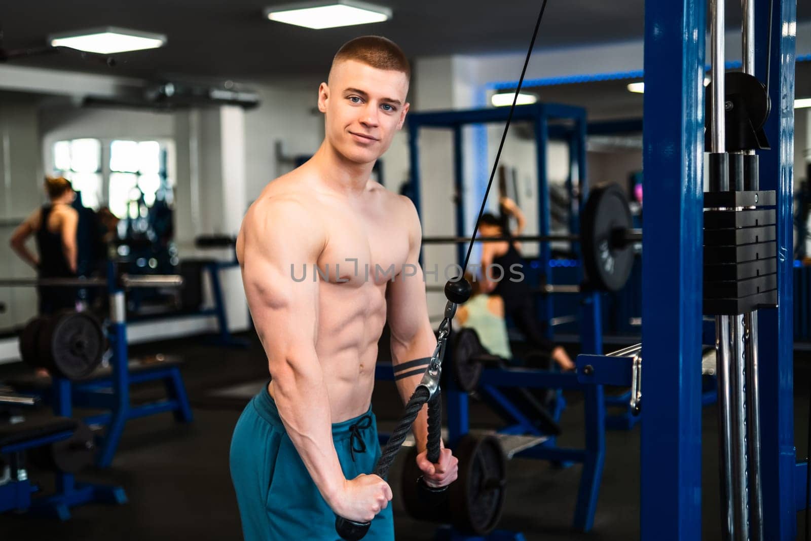 Portrait of man training triceps with cable machine at the gym.