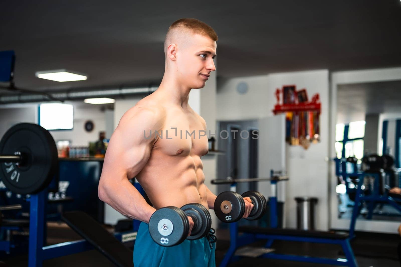 A young man lifting weights in a gym. Professional bodybuilder training in the gym