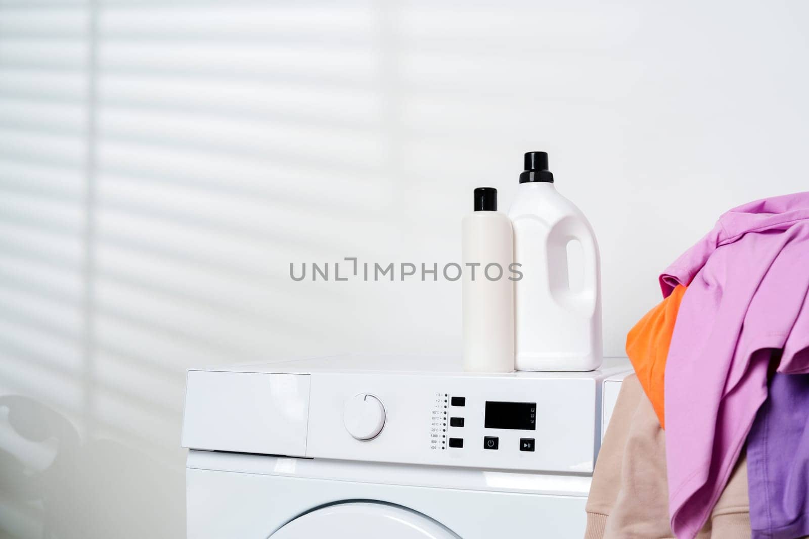 This image shows two white washing machines with a pile of colorful clothes sitting on top of one of them.