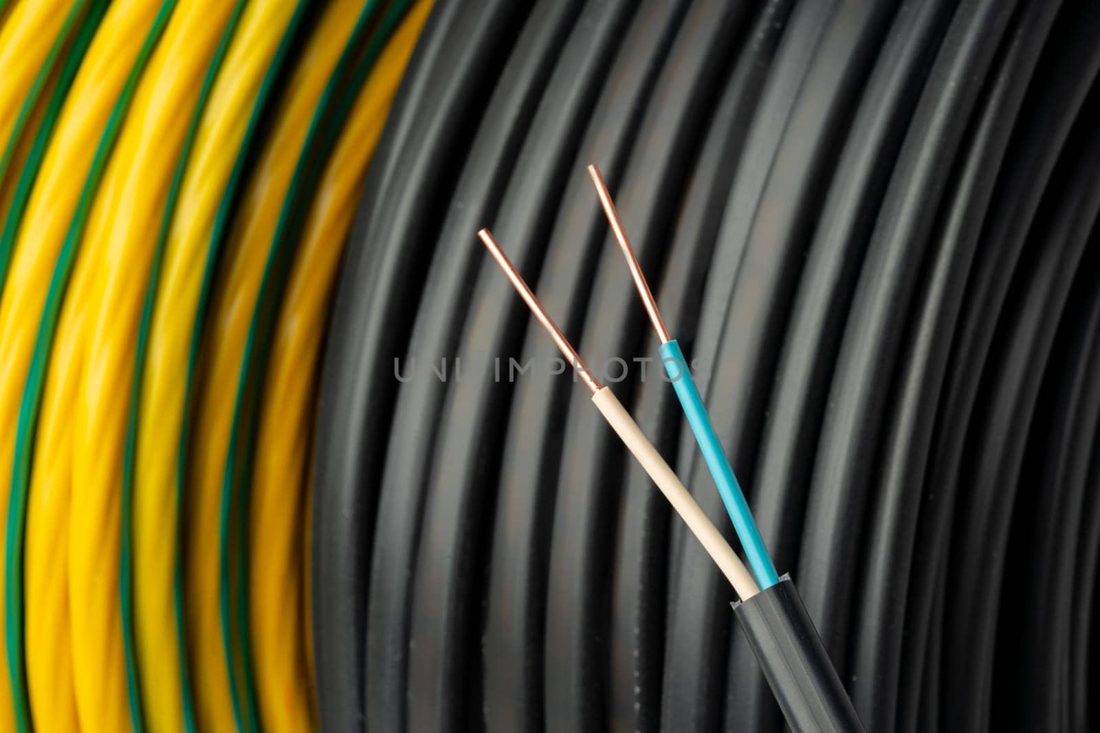 A close-up photo of a coil of black electrical wire with blue and white wires running along the outer edge.