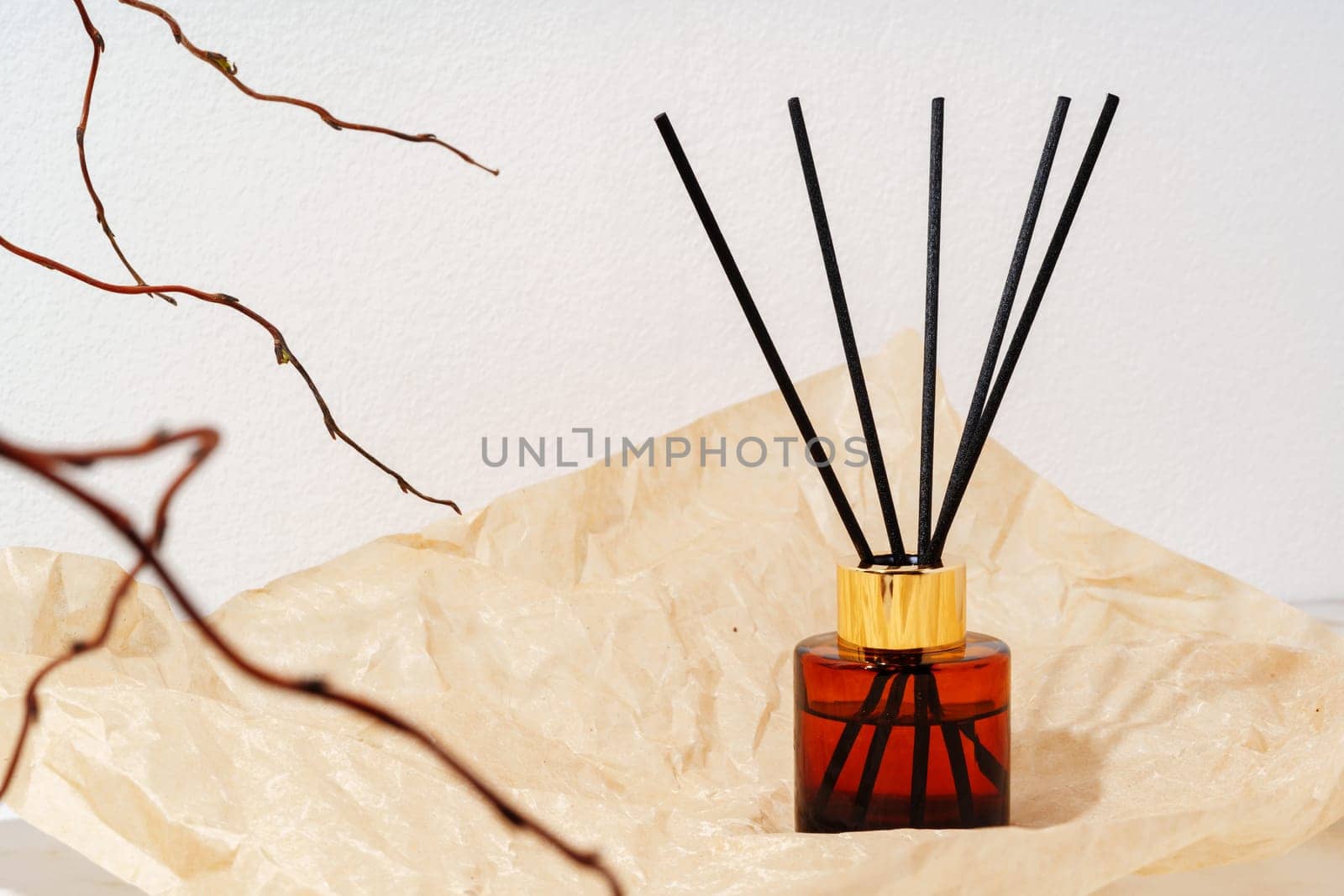 A glass diffuser bottle with wooden sticks sits on a wooden tabletop.