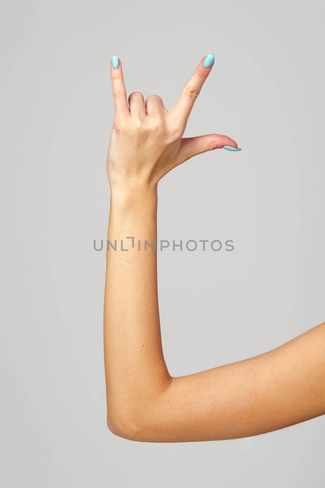 Womans Hand With Blue Nail Polish on gray background close up