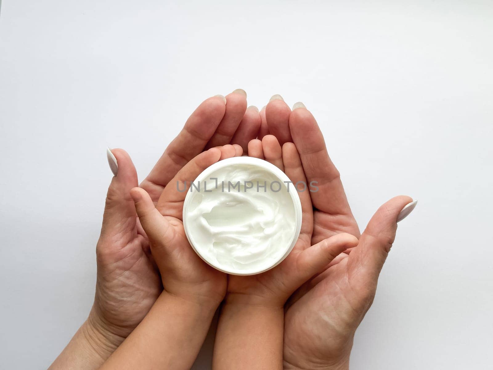 Close up of woman and childs hands holding hand cream on white background. Skincare and moisturizing concept. Design for healthcare, beauty, wellness, and family care poster. High quality photo