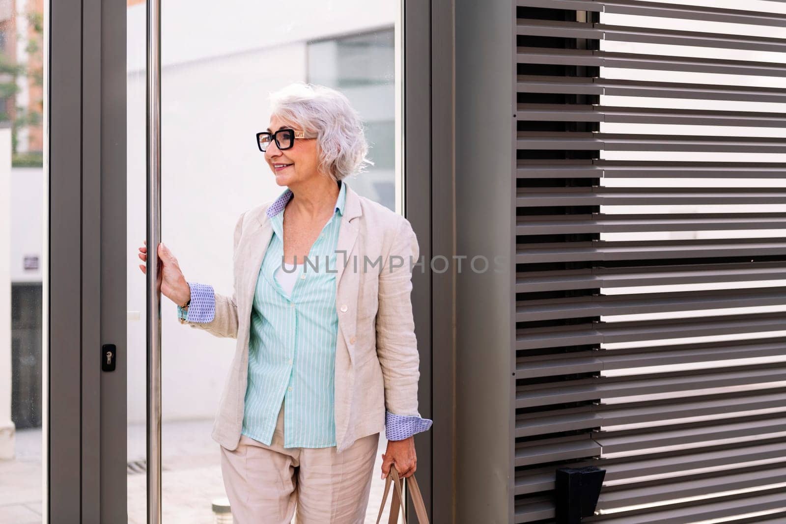 smiling mature woman coming out of the home portal, concept of happiness and active lifestyle in adulthood, copyspace for text