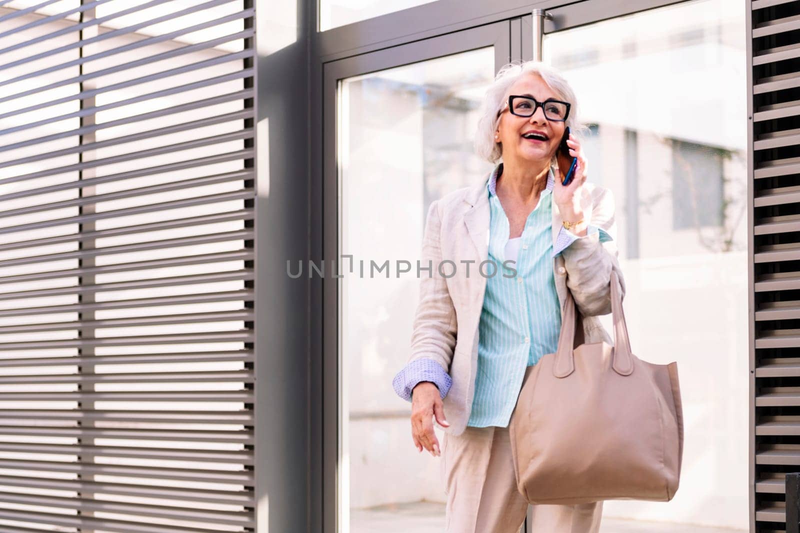 smiling mature woman coming out of the home portal while talking on mobile phone, concept of happiness and technology of communication, copyspace for text