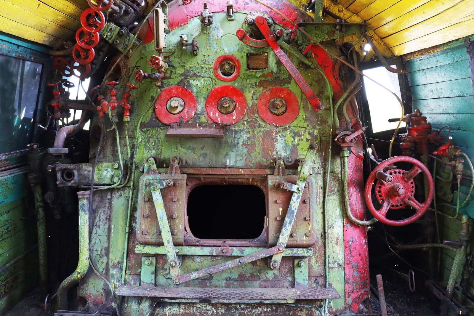 Open door to the furnace of a steam engine. The interior is inside the locomotive, there are metal fittings. Background. Texture. Equipment from taps, valves, levers.