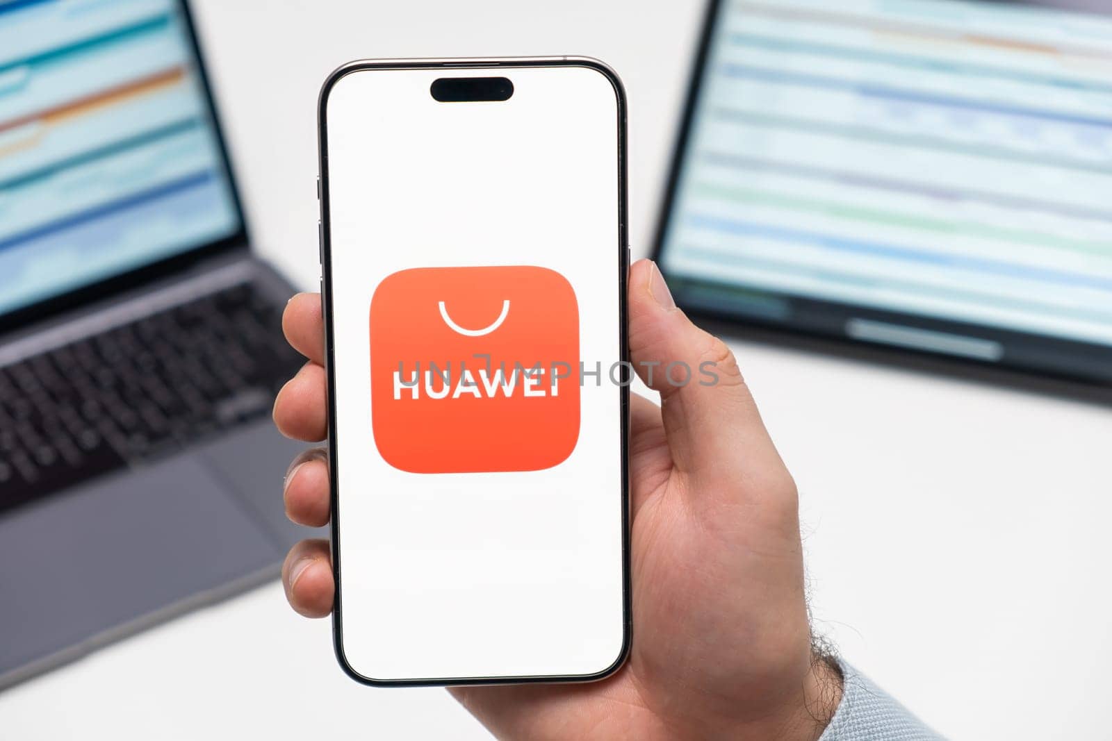 PRAGUE, CZECH REPUBLIC - JANUARY 21 2024: Huawej logo on the screen of smartphone in mans hand on the workplace background.