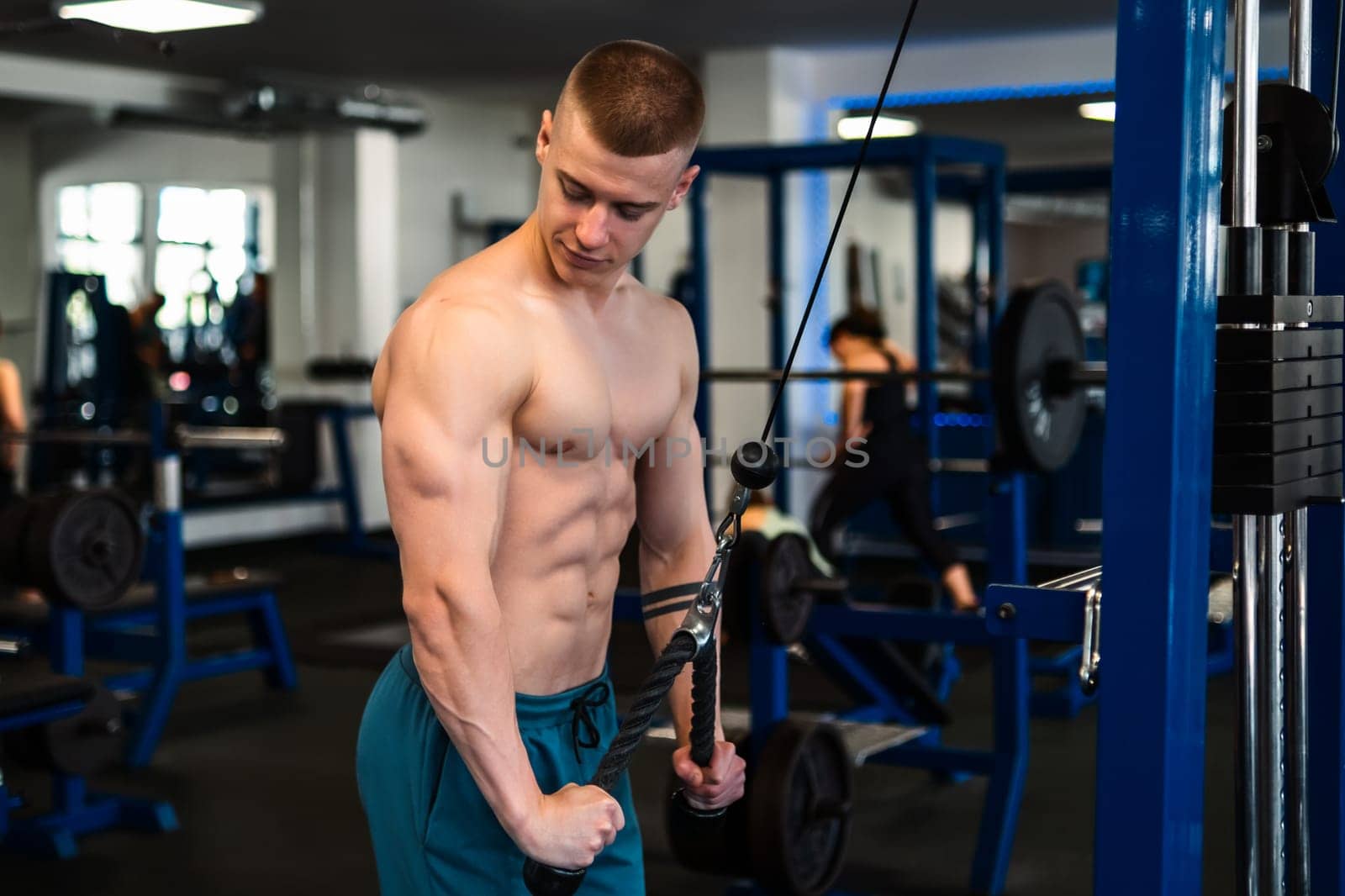 Bodybuilder working out on cable machine in gym. Training of triceps
