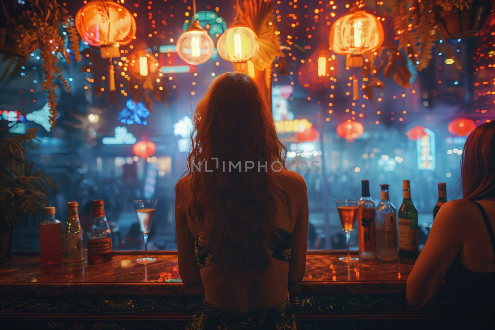 A woman with long curly hair sits at a bar counter with drinks and a view of a city street lit by colorful lanterns. The image is taken from behind the woman, and the focus is on the back of her head and shoulders as she leans forward with her hands resting on the counter.