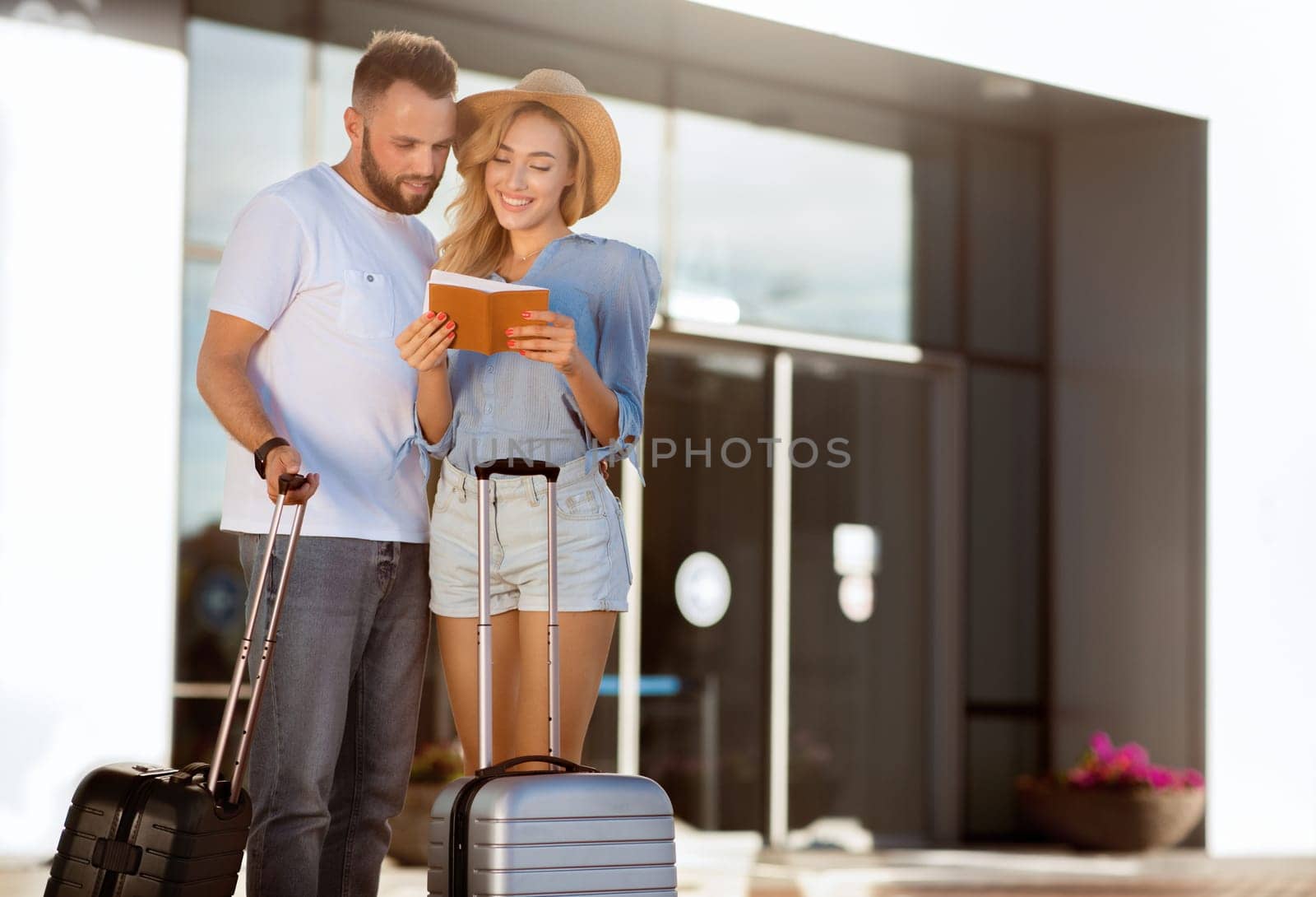 Traveling Concept. Portrait of lovely spouses checking tickets before their vacation standing near airport, copy space