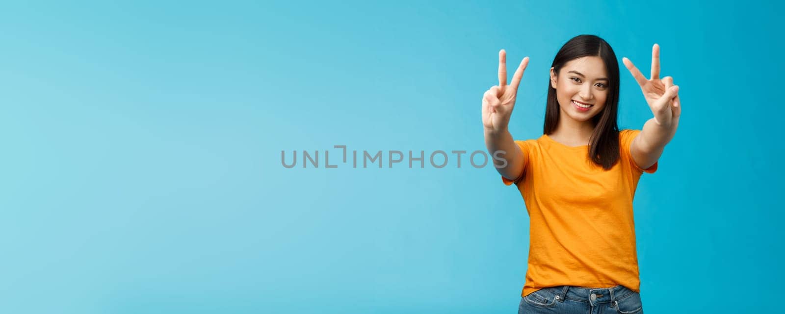 Positive upbeat cute asian girl believe win, aim success extend hands show victory, peace sign smiling broadly, have happy enthusiastic mood, spend carefree vacation travel abroad value pacifism by Benzoix