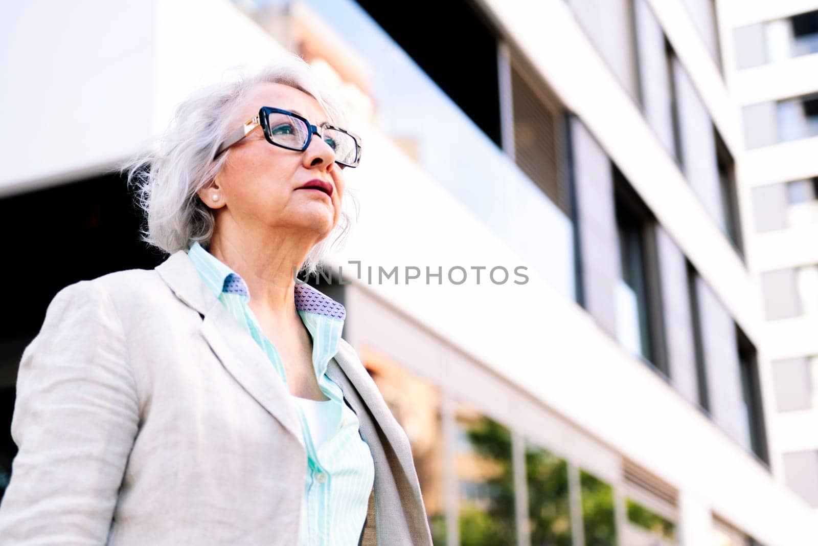 portrait of a stylish mature woman walking next to a building, concept of urban lifestyle in adulthood, copyspace for text