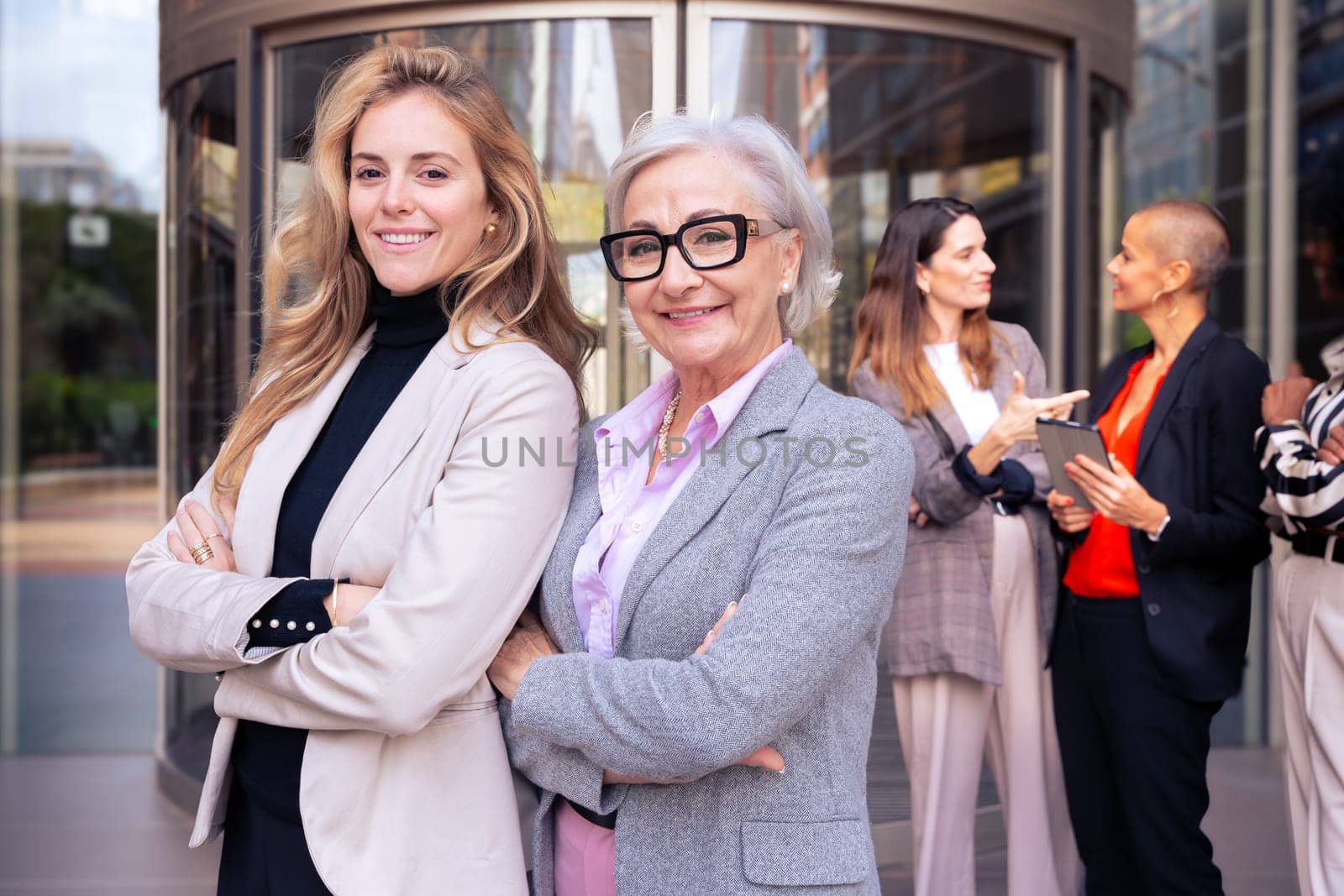 Happy businesswomen standing side by side with their arms crossed. Suitable for team, friendship and diversity concepts.