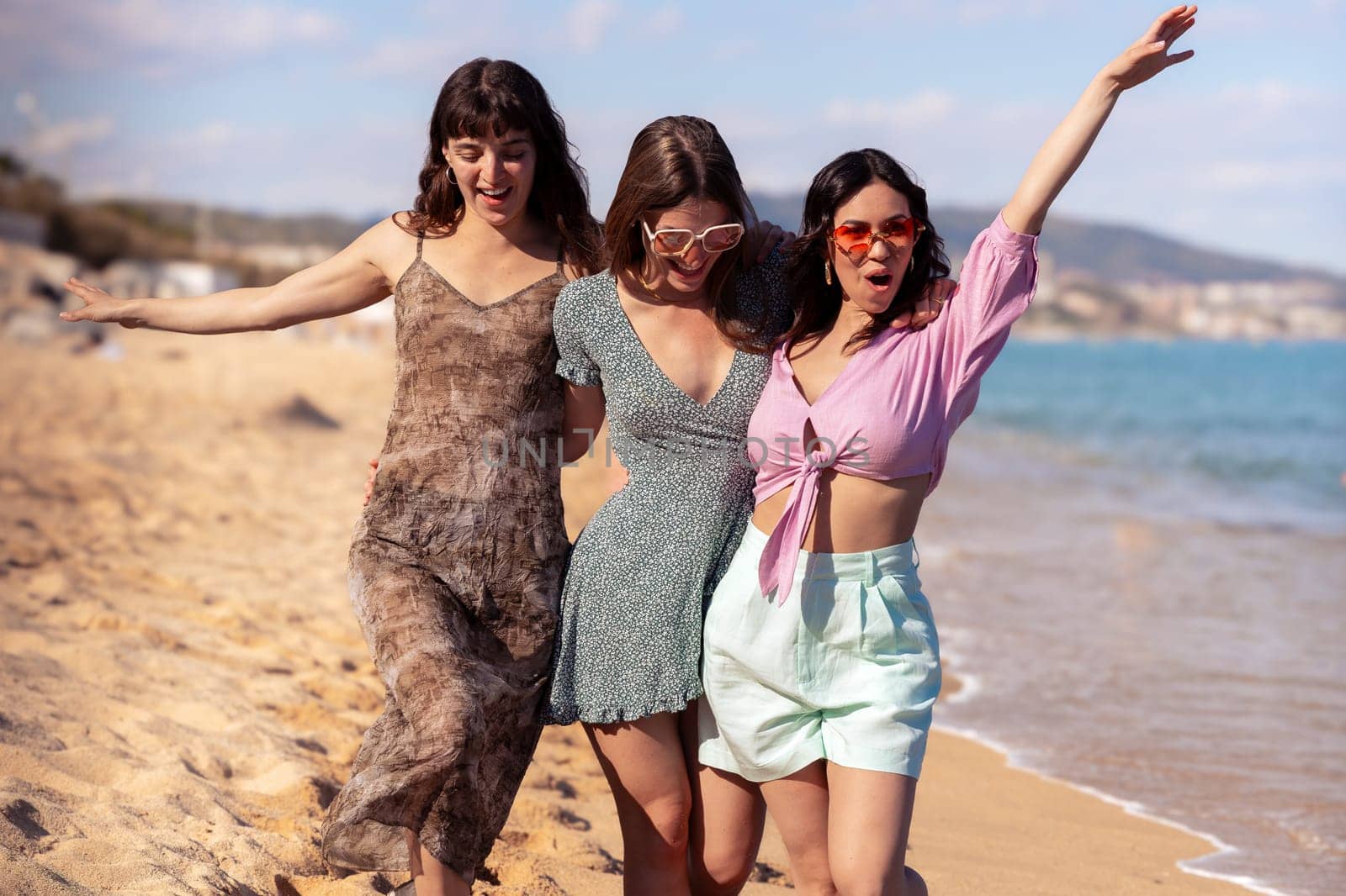 Cheerful multiethnic friends with sunglasses happy on vacation on the beach, looking at the camera.