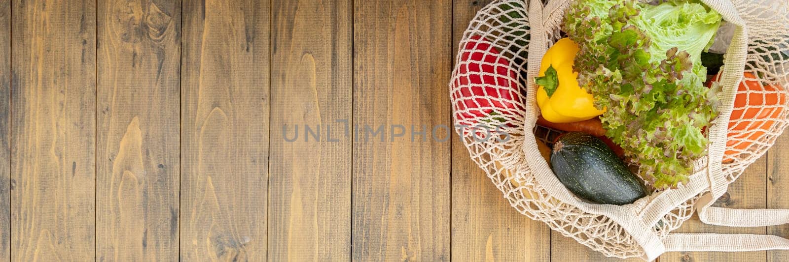 Banner of bell peppers, zucchini and lettuce in a reusable bag. fresh vegetables in eco bag on wooden background. eco concept and respect for nature. copy space. top view