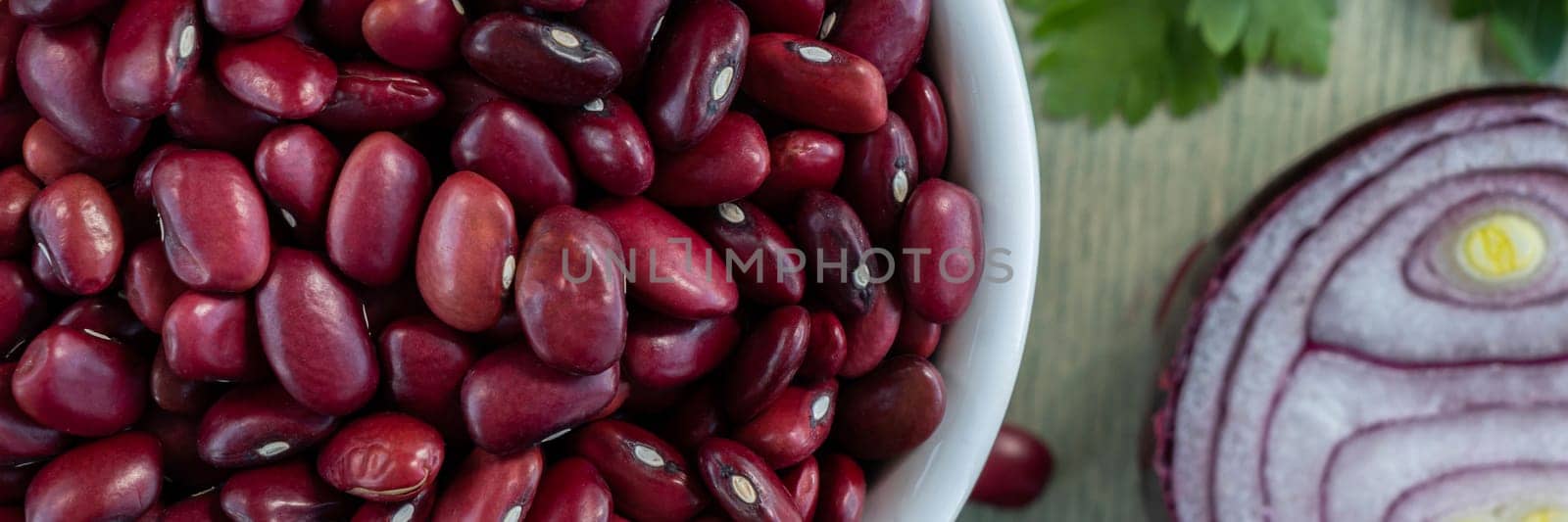 Banner of red beans in white plate with onion and parsley. close up red beans with spices on a green wooden background. Flat lay. Top view