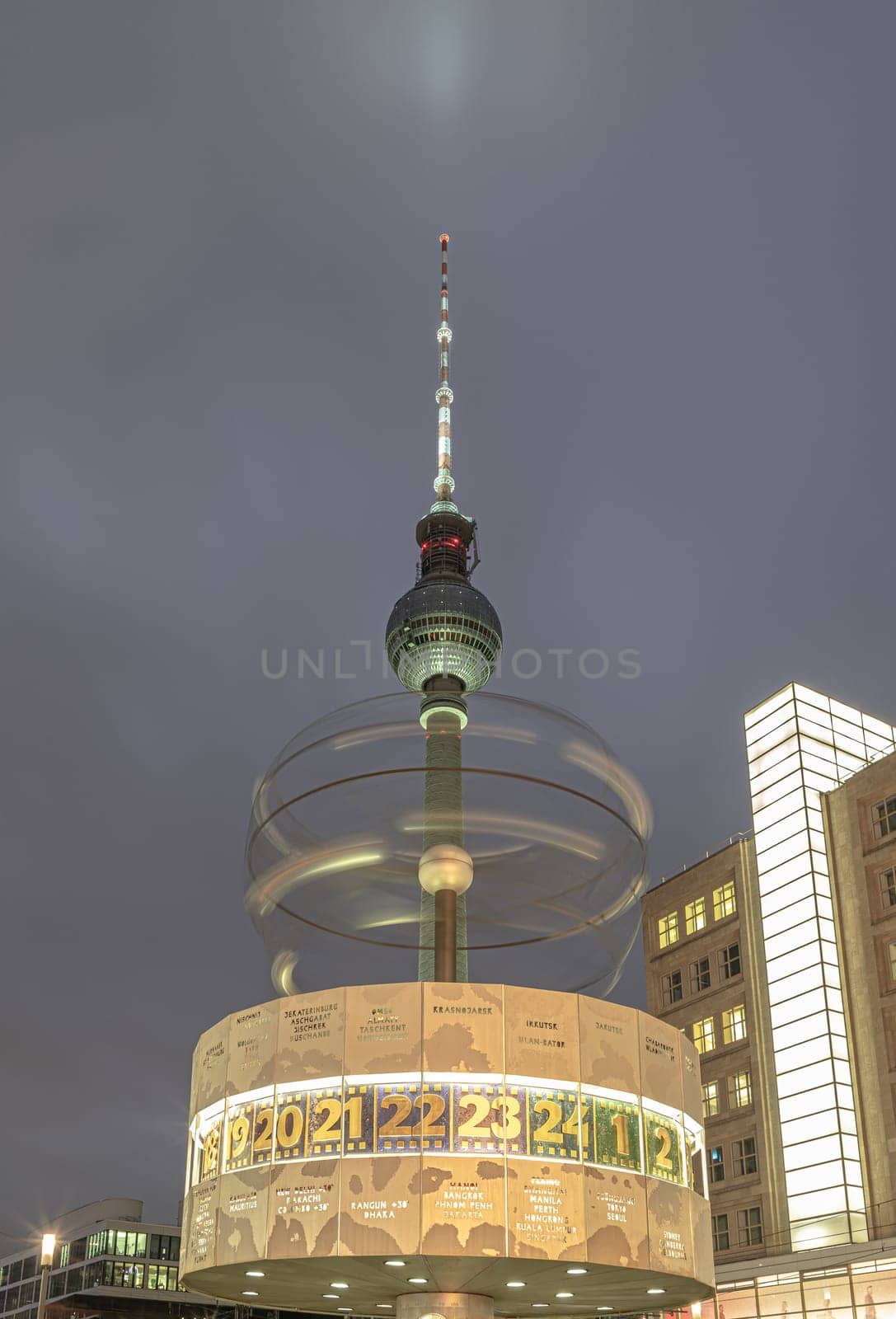 Berlin, Germany - Dec 18, 2023 - Night view of Urania-Weltzeituhr or The World Clock - Revolving sphere in front of Berlin Television Tower (Fernsehturm) near Alexanderplatz square in Berlin, A Tourist attraction and Meeting place, Copy space, Selective focus.