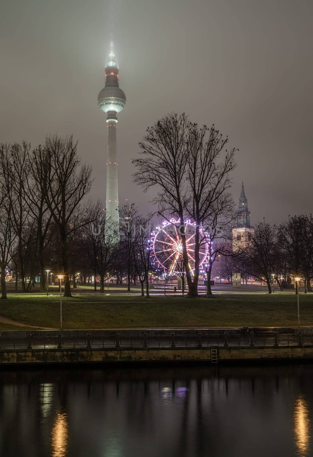 Berlin, Germany - Dec 19, 2023 - View of Famous Berlin Television Tower (Fernsehturm), Mary's Church Steeple and Ferris Wheel of Night Christmas Market near Alexanderplatz in Berlin, Copy space, Selective focus.