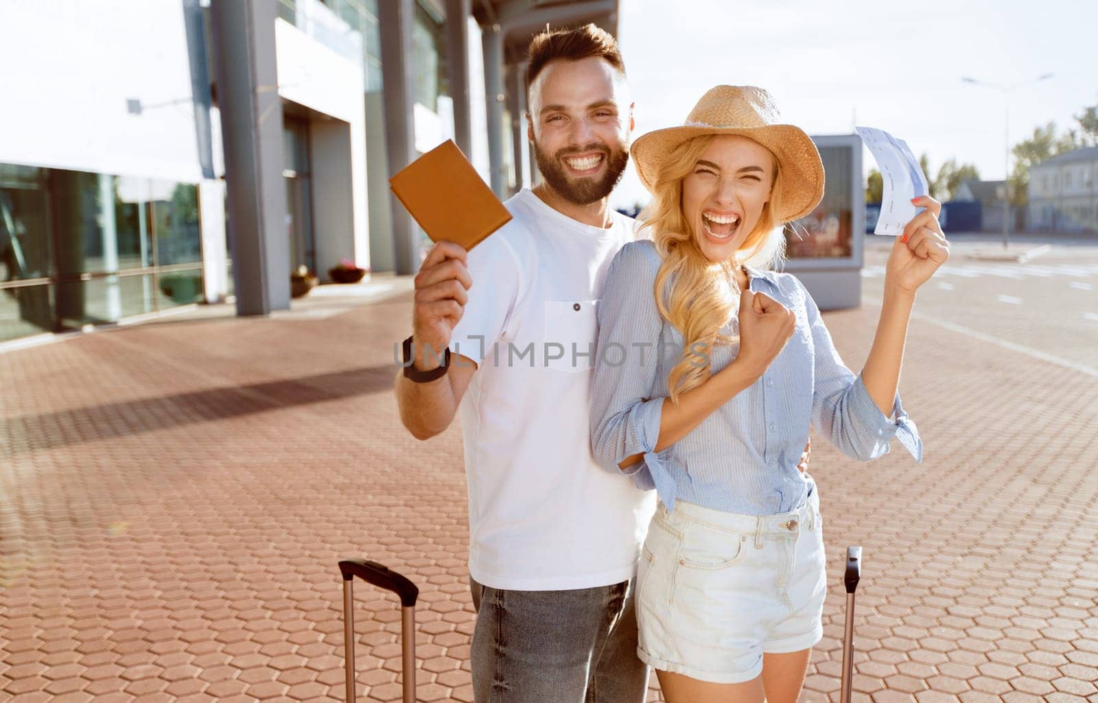 Ready For Vacation. Excited spouses with suitcases showing boarding passes and passports, standing near airport