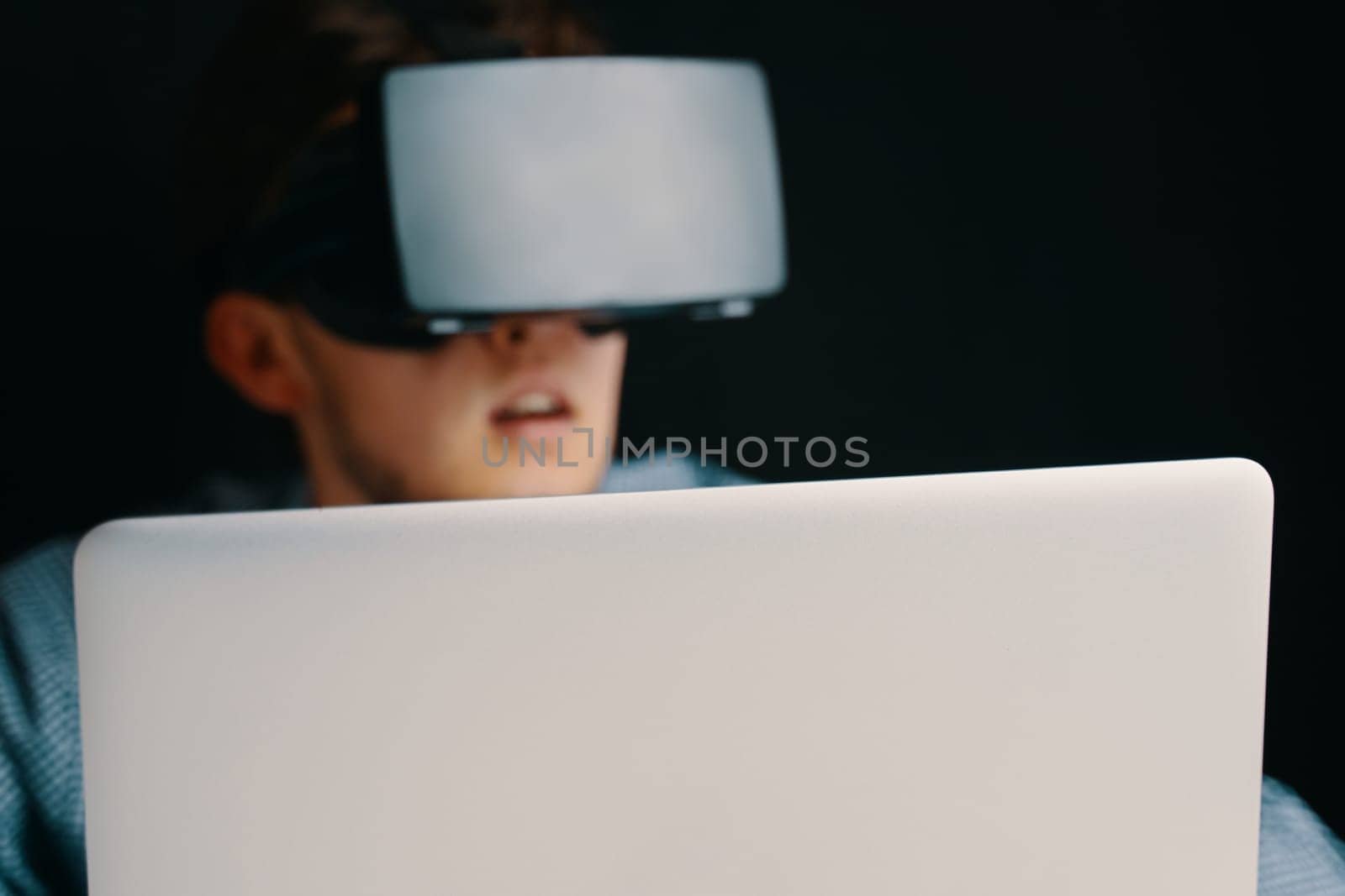A young person in a VR headset with a laptop, symbolizing advanced technology and immersive digital experiences